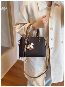 Detail shot of vintage dark brown handbag with crossbody strap and horse charm