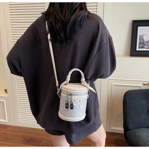 Détail d'un sac seau blanc avec motifs géométriques et poignée enroulée de soie