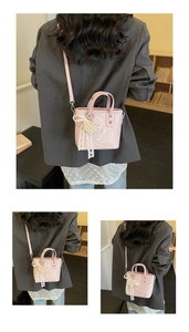 Dettaglio mini borsa a secchiello rosa con fiocco in pizzo, ciondolo perla e pelle morbida
