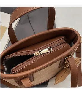Détail de la fermeture éclair dorée sur le sac seau bicolore en cuir et tissu