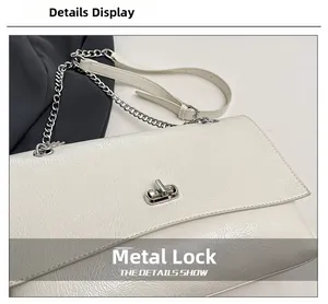 Gros plan du sac en cuir blanc avec fermoir rotatif argenté et détail de la chaîne