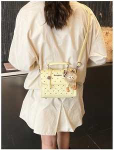 Polka dot handbag with plush charm shown in a lifestyle casual crossbody style