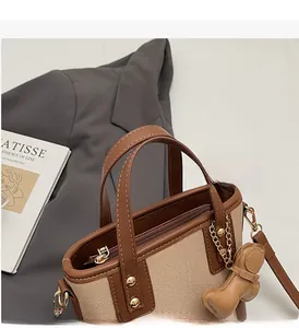 Détail du sac seau en toile avec garniture en cuir marron et breloque ours mignon