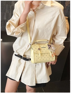 Polka dot crossbody bag in bright yellow with a plush leopard-ear charm on model
