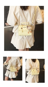 Detailed view of yellow polka dot crossbody bag with plush monster charm and top handle