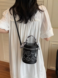 Sac seau noir élégant avec motifs géométriques et poignée en foulard porté par modèle