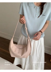Detail of light pink crescent shoulder bag with lychee texture and zipper closure