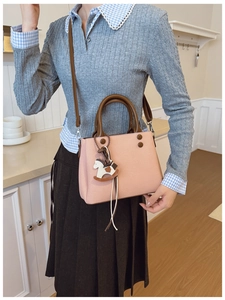 Detail of pink crossbody bag with brown straps and cute rocking horse charm accessory