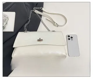 Détail du sac sous le bras blanc avec fermoir rotatif argenté et accessoires en cuir