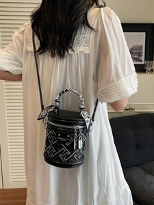 Sac seau noir élégant avec motif géométrique et poignée en foulard sur un modèle