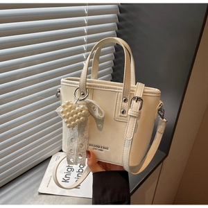 Dettaglio della borsa tote in pelle PU bianco avorio con ciondolo cuore di perle e pizzo