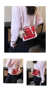 Detail of red polka dot handbag with a white handle and a cute fuzzy monster keychain