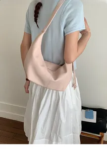 Pale pink soft leather crescent shoulder bag styled with light blue casual outfit
