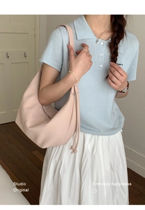 Detail of light pink pebble leather texture and drawstring on a hobo shoulder bag