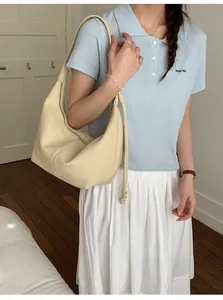 Beige soft leather hobo bag worn by model in a minimalist lifestyle setting