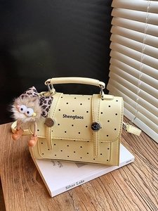 Minimalist yellow polka dot handbag with creative plush monster charm and top handle