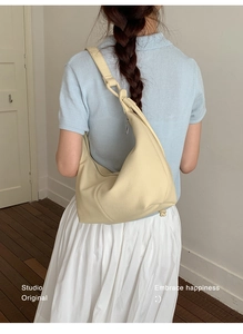 Detail of cream-colored dumpling bag with lychee texture and metal zipper closure