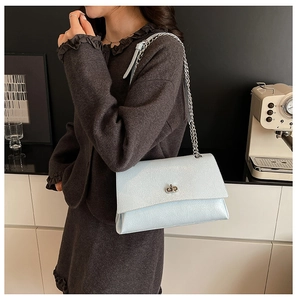 Détail du sac à chaîne bleu clair nacré avec fermoir rotatif argenté et bandoulière en cuir