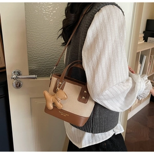 Détail du sac seau rétro bicolore avec charm chien en cuir et lettrage doré chic