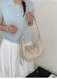 Detailed view of cream soft leather dumpling bag texture with decorative side knots