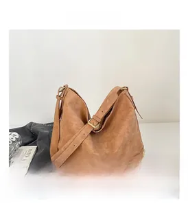 Dettaglio borsa tote in pelle opaca marrone con borchie dorate e tracolla regolabile