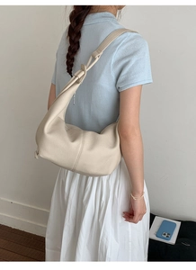 Detailed view of cream-colored hobo bag featuring vertical stitching and pebble grain texture