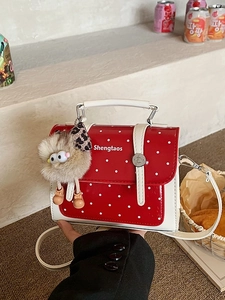 Red polka dot mini handbag with plush monster charm and shiny finish crossbody strap