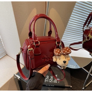 Détail du sac en cuir verni bordeaux avec motif poney et pendentif en peluche chien