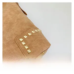 Dettaglio della borsa tote in pelle marrone con borchie quadrate dorate e cuciture di precisione