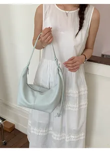 Detail of light blue hobo bag with pebble leather texture and decorative knotted strap