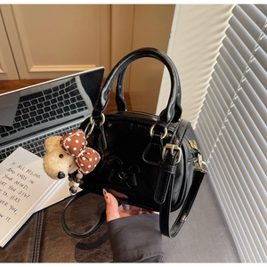 Détail du mini sac Boston en cuir verni noir avec gaufrage chien et breloque ours