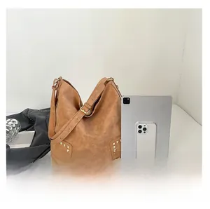 Borsa hobo marrone con borchie accanto a un tablet per riferimento dimensionale