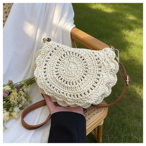 Detail view of cream crochet shoulder bag with spiral pattern and leather strap on a chair
