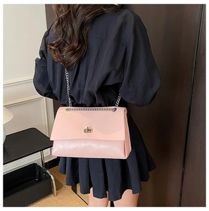 Vue détaillée du sac rose brillant avec chaîne et fermoir rotatif argenté