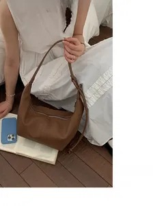 Detail of dark brown lychee leather shoulder bag with sleek zip and minimalist strap