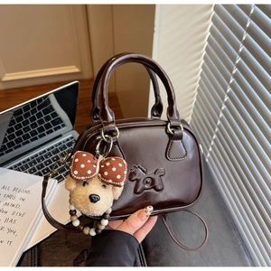 Détail d'un sac Boston marron foncé avec gaufrage cheval et breloque ours en peluche