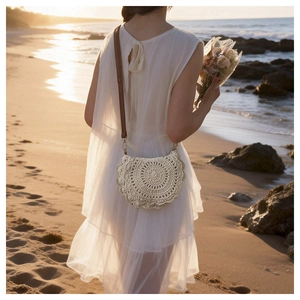 Detail of a semi-circular straw woven saddle bag with delicate radial patterns on beach