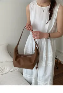 Close-up of a vintage brown pleated hobo bag with adjustable strap and silver zipper detail