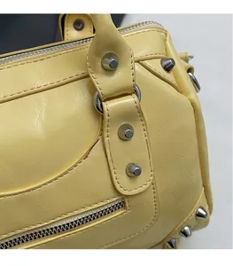 Close-up of pale yellow Boston bag showing silver rivets and premium leather texture