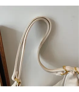 Dettaglio della tracolla in pelle bianco avorio con elegante fibbia in metallo dorato