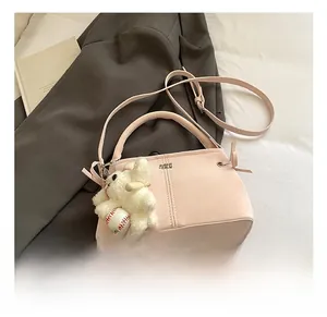 Detail of pink suede handbag with logo and cute plush bunny charm on gray suit