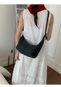 Detail of the knotted shoulder strap and textured leather finish on a black hobo bag