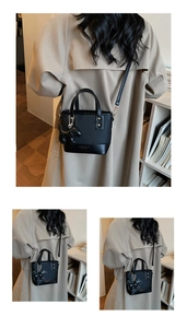 Détail d'un sac bandoulière en cuir noir avec pendentif chien et boucle métallique