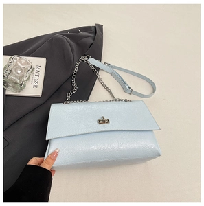 Détail du sac à bandoulière bleu clair en cuir texturé avec chaîne argentée et fermoir