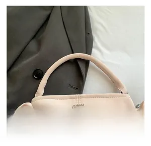 Detail of light pink leather handbag with smooth handle and metal logo on blazer