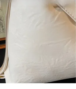 Dettaglio borsa tote bianco sporco con trama a grana fine e finiture dorate