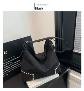 Dettaglio di una grande borsa Hobo nera con rivetti dorati e texture opaca fine