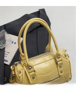 Detail of yellow rivet handbag with woven handles and tassels in a lifestyle setting