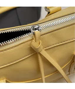 Detail of yellow leather pillow bag with silver metal zipper and long leather tassel pull