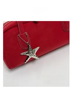 Detail of red leather baguette bag with silver starfish charm and precise stitching